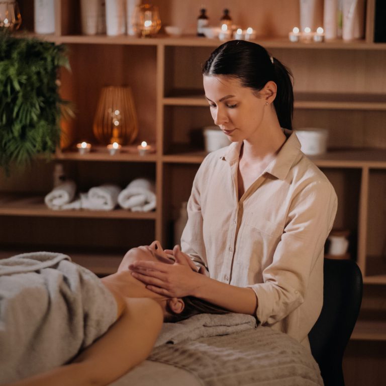 A cosmetologist girl does a facial and neck massage to a girl in the office for skin elasticity.