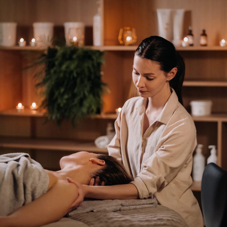 A cosmetologist girl does a facial and neck massage to a girl in the office for skin elasticity.