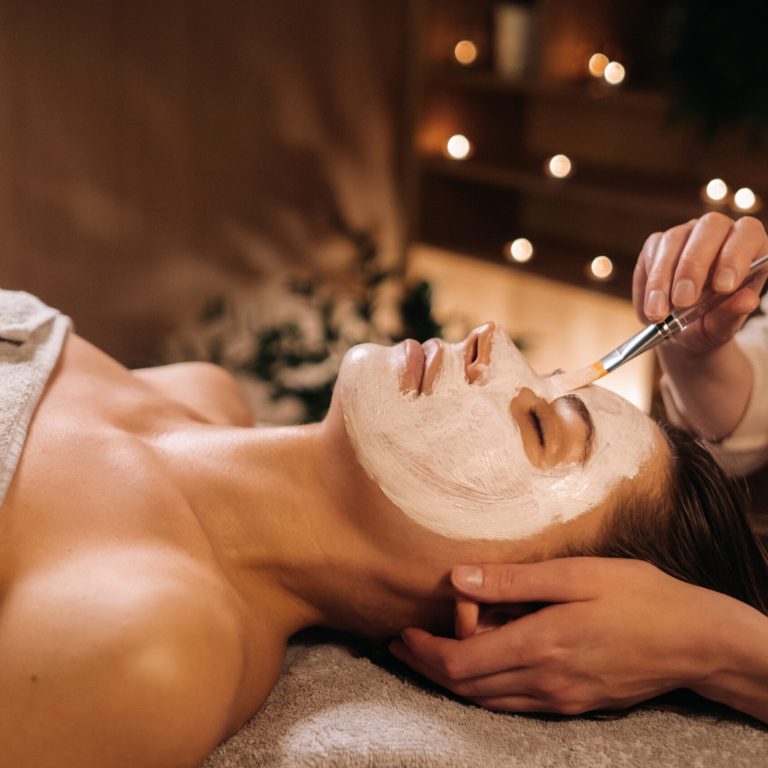 A cosmetologist makes a mask for a woman's face to rejuvenate the skin. Cosmetology.