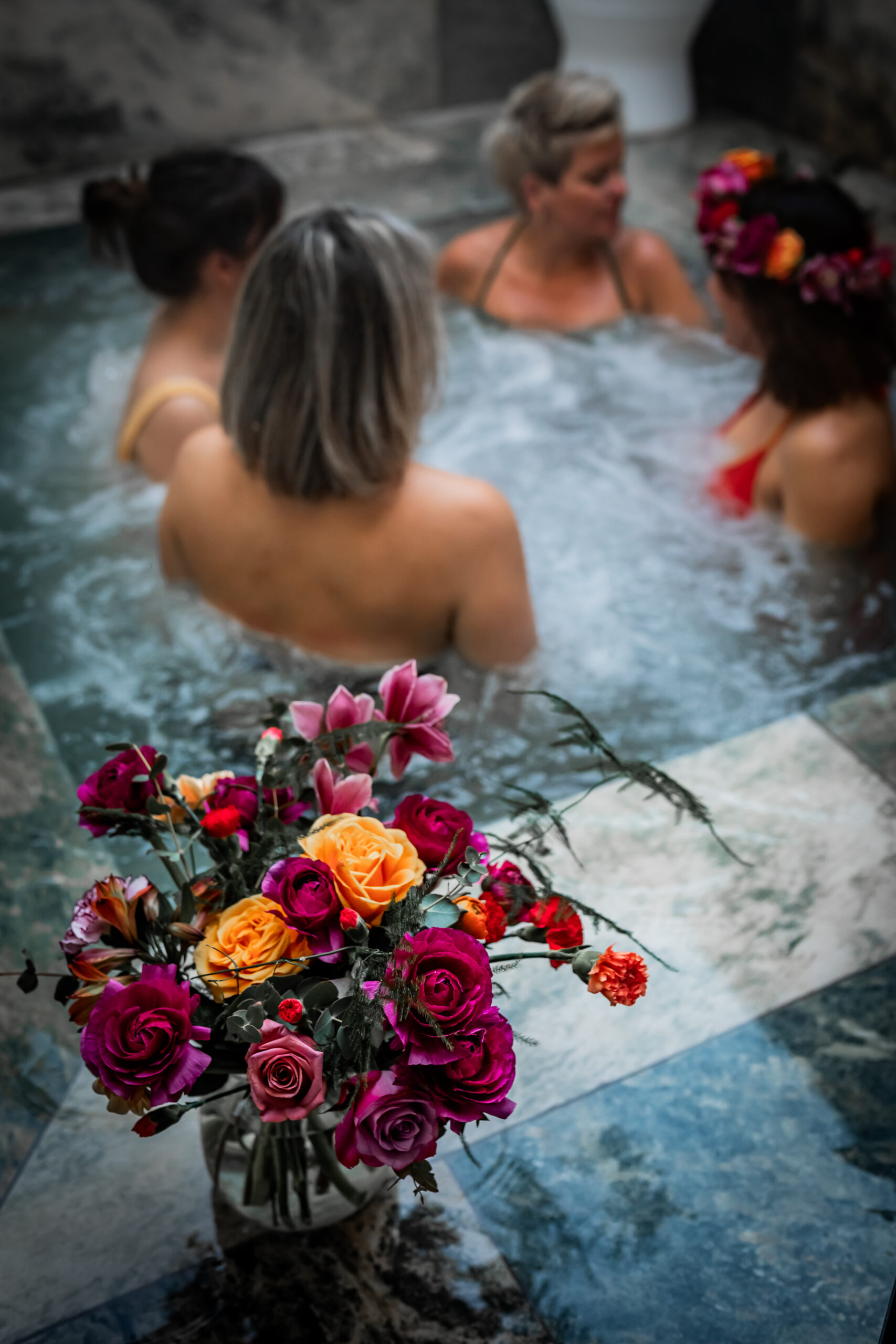 Amies dans le jacuzzi extérieur, bouquet de fleurs au premier plan