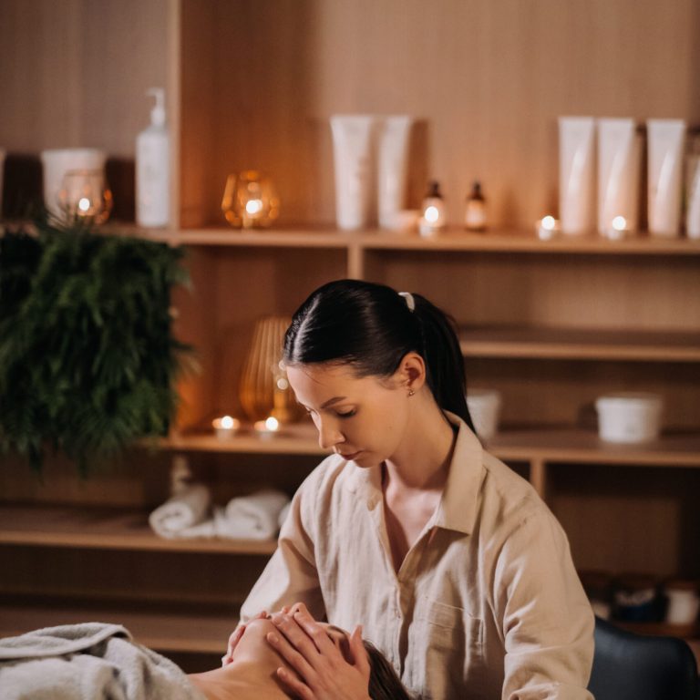 A cosmetologist girl does a facial and neck massage to a girl in the office for skin elasticity.